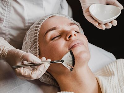 Woman receiving facial treatment with fan brush