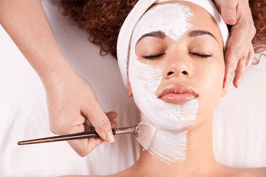 Woman receiving facial mask application